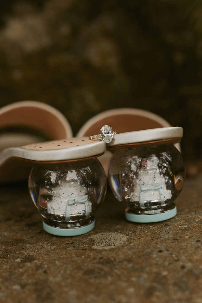 A pair of shoes with small wedding cakes in the heel are shown in a detail photo from an olympic national park wedding