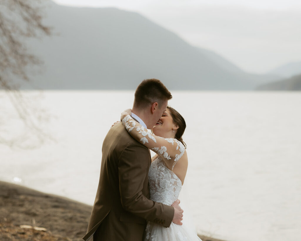 Newlyweds share a kiss on the shore at their Lake Crescent wedding
