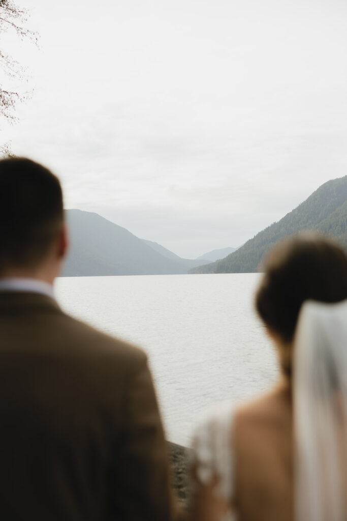 Newlyweds look out of over Lake Crescent following their PNW elopement on the shore