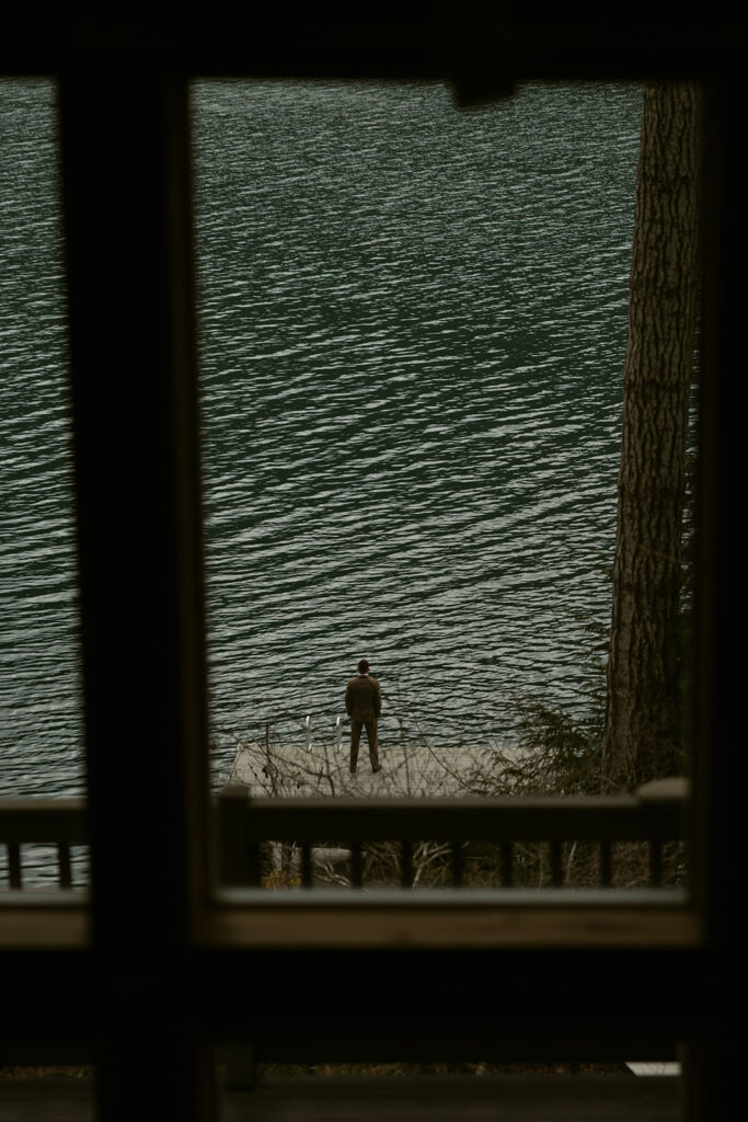 A groom awaits the first look of his bride from the shore of Lake Sutherland taken before their Olympic National Park Wedding