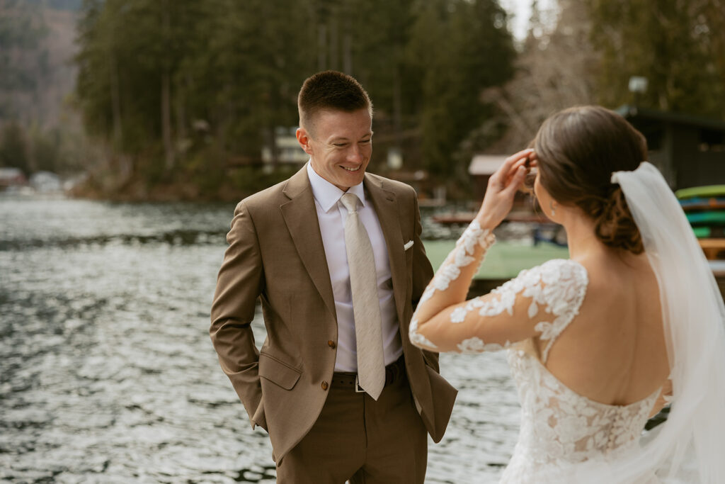A groom smiles during a first look at his bride in her wedding gown in a photo take by an olympic national park elopement photographer
