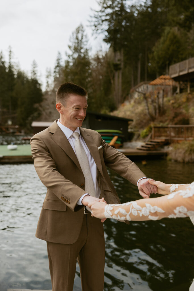 A groom wearing a brown suit and a camel tie admires his bride during a first look shot taken by olympic national park elopement photographer, Tessa Marie Co
