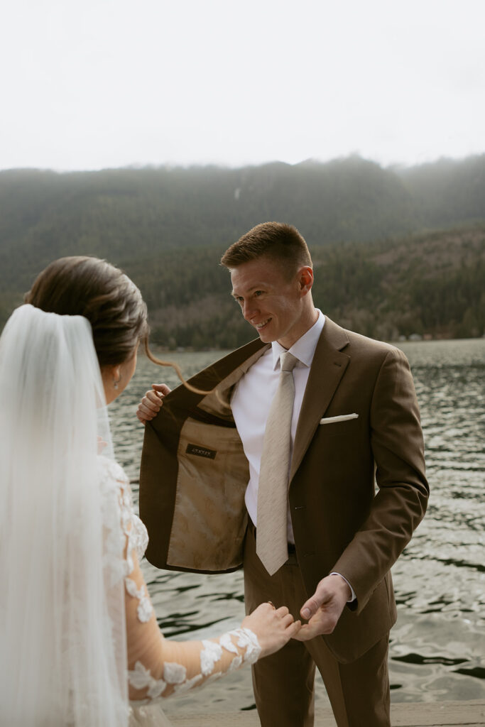 A bride admires the surprise embroidery on the inside of her groom's suit jacket before their PNW elopement