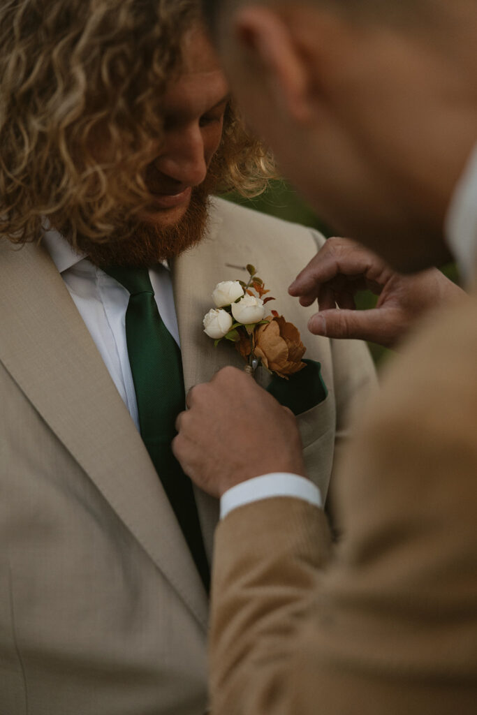 A groom has his boutonniere pinned to his lape before his Mt Baker elopement