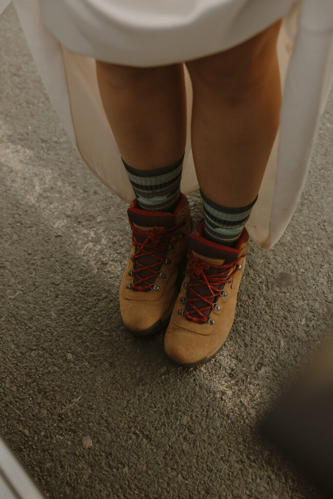 A bride lifts her wedding dress to reveal hiking boots worn for her mt baker elopement