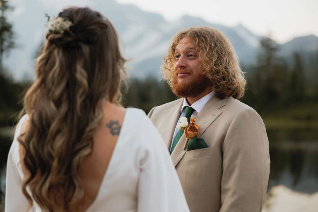 A man in a tan suit looks at his bride before their Washington elopement in Snoqualmie National Forest