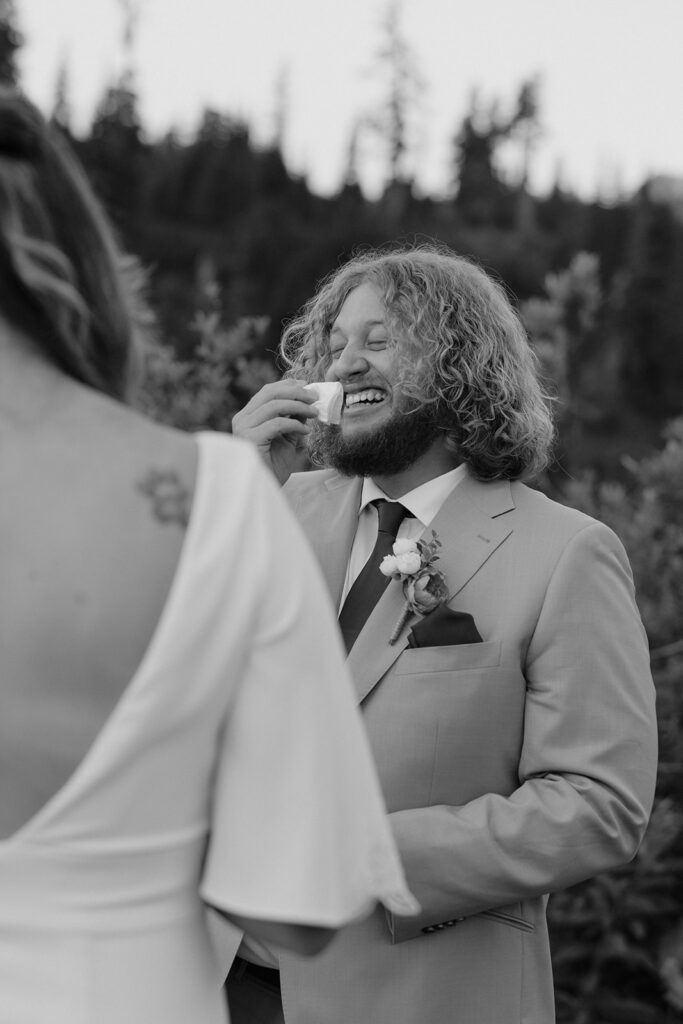A groom dabs his eyes with a tissue in a black and white photo taken at a Washington elopement