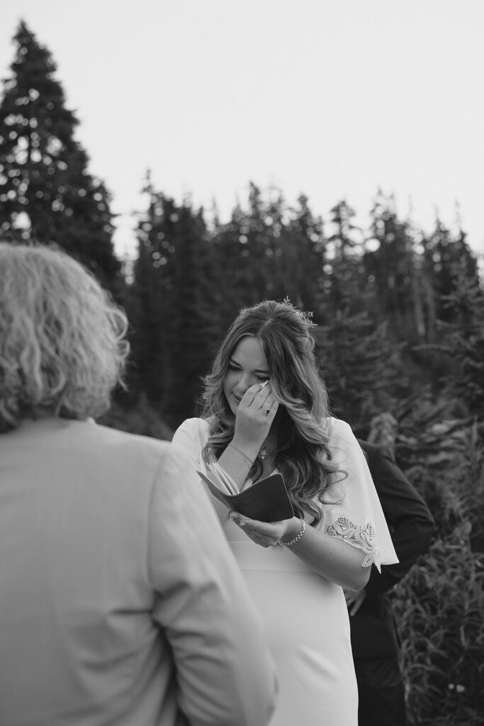 A bride dabs her eyes with a tissue as she reads her handwritten vows as she and her groom elope in Washington