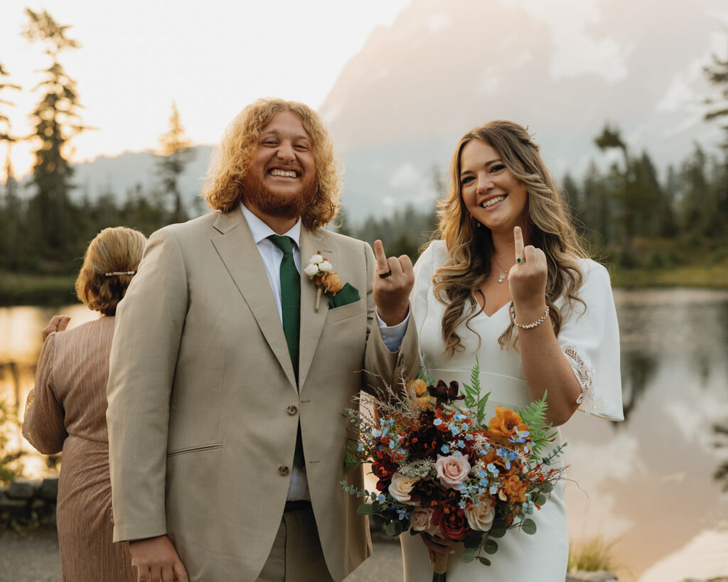 Newlyweds show off their wedding rings in their wedding attire following their Mt Baker elopement ceremony