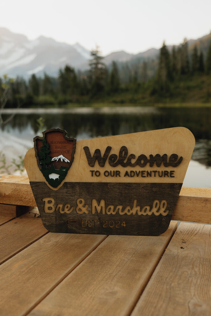 A wooden sign reads 'Welcome to our adventure' with the NPS logo with bagley lakes in the background