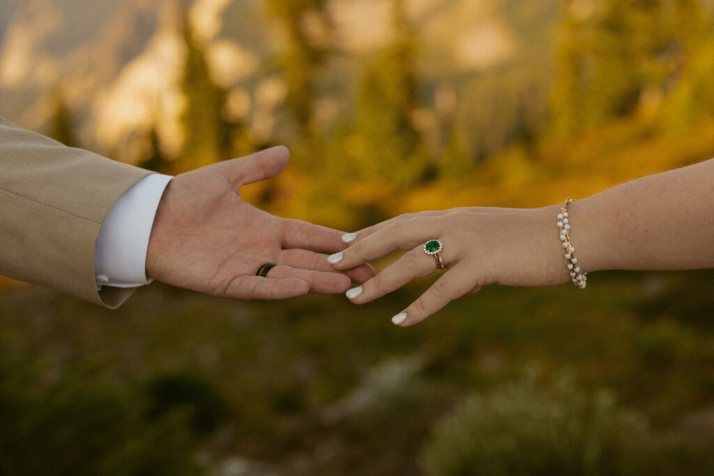 Newlyweds reach their hands toward each other in a detail shot featuring their rings following their Washington elopement