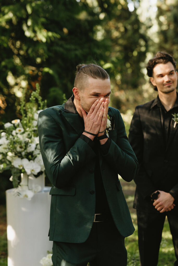 A groom standing at the altar reacts to seeing his bride at their Hoyt Arboretum wedding 