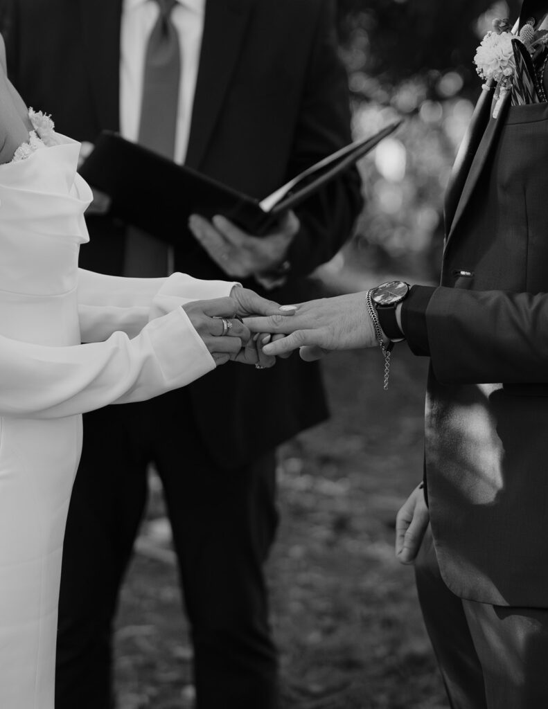 A black and white image of a ring exchange at a Hoyt Arboretum wedding in Portland OR