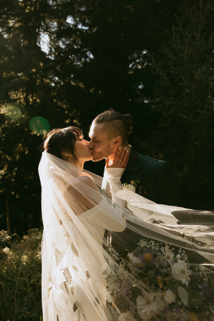 Oregon wedding photography depicting newlyweds sharing a kiss in Hoyt Arboretum in this editorial style photo