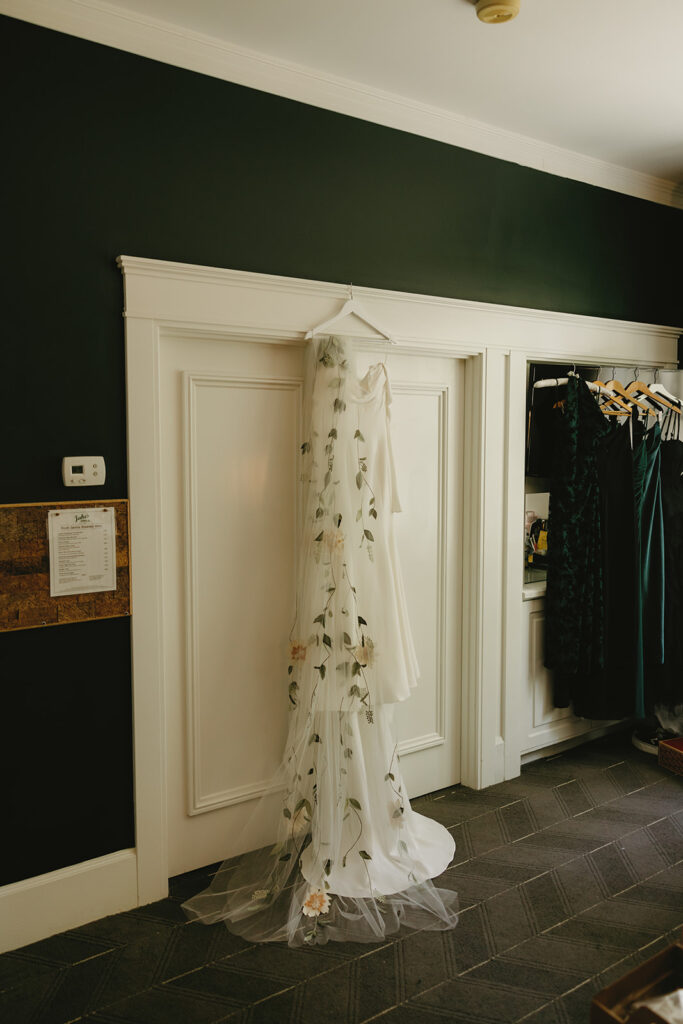 A wedding dress hangs against a white wall in a photo taken at The Sentinel
