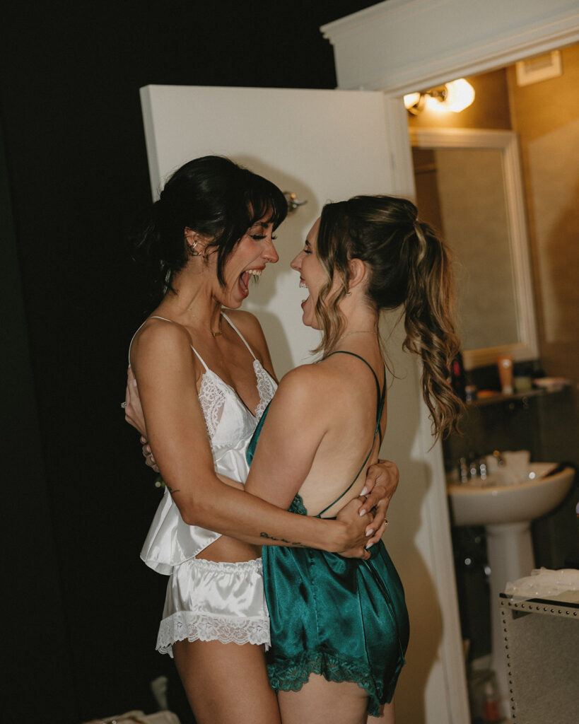 A bride hugs one of her bridesmaids excitedly while getting ready for her Hoyt Arboretum wedding
