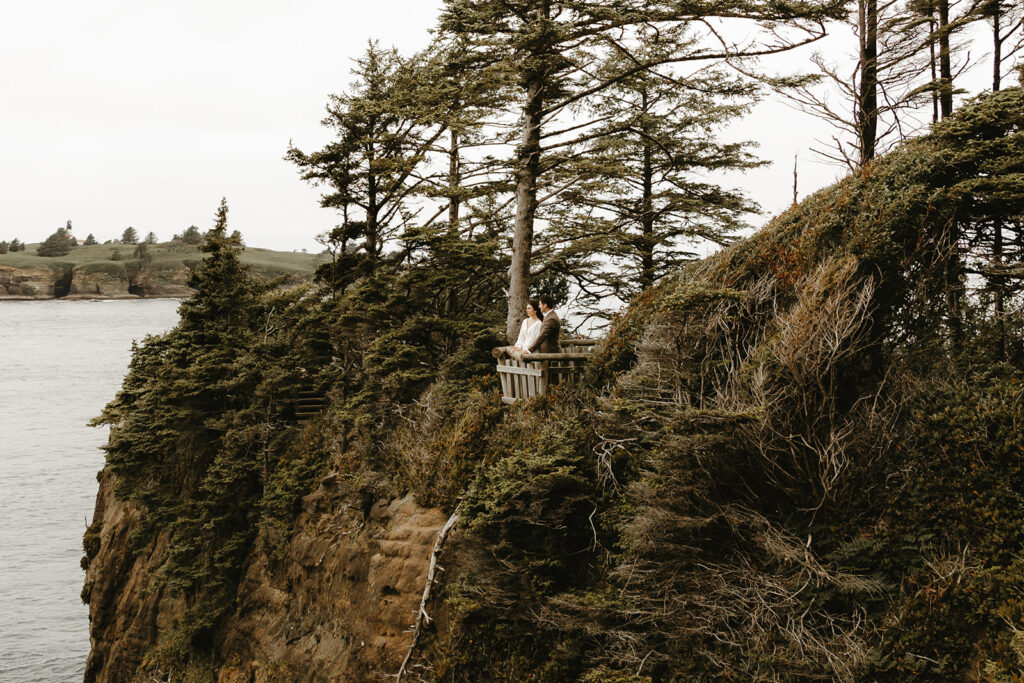 Newlyweds are photographed in their wedding attire on an overlook at Cape Flattery following their national park elopement