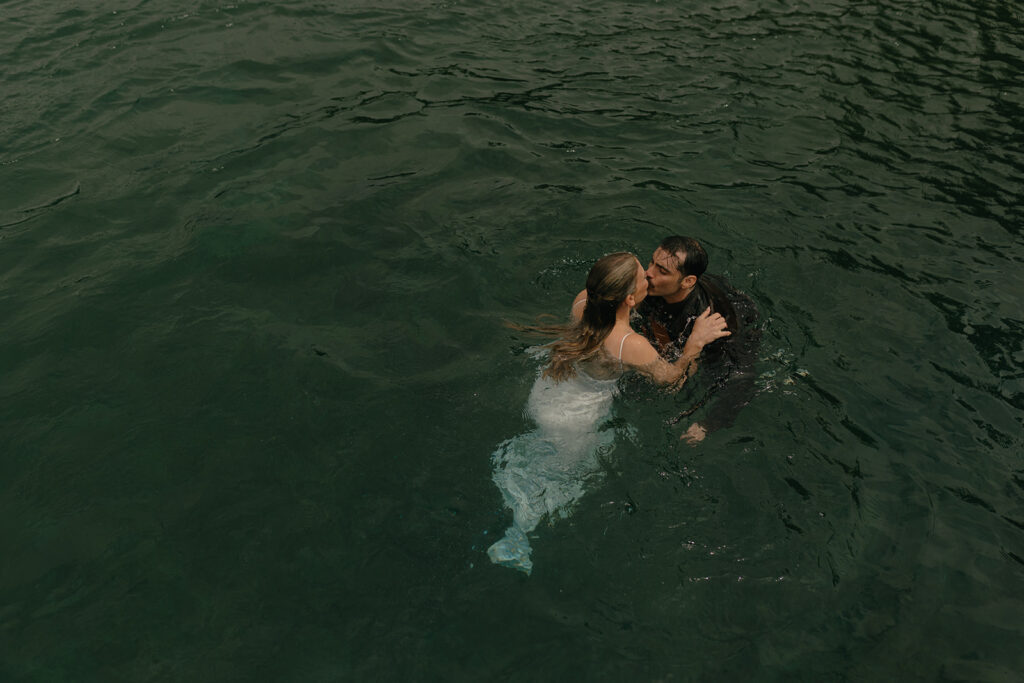 Newlyweds go for a swim in Lake Crescent in their wedding attire following their Olympic National Park wedding