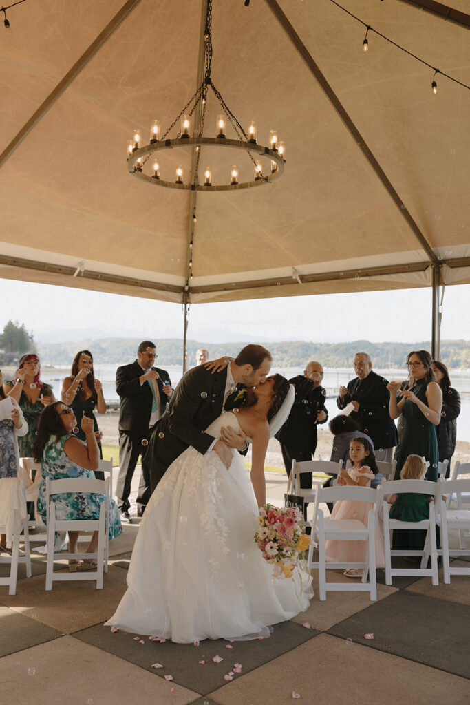 A groom dips his bride in her white wedding gown at their Alderbrook Resort elopement ceremony