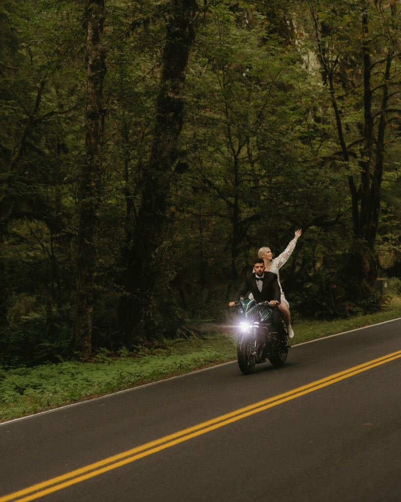 Newlyweds ride a motorcycle in their wedding attire following their Washington elopement.