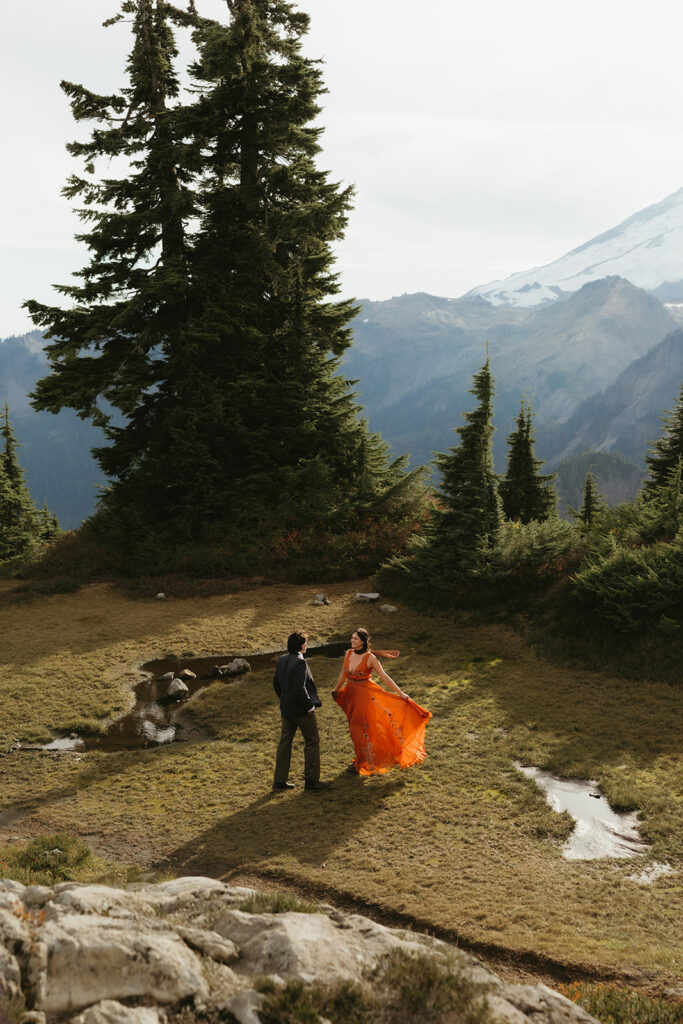 A bride wearing an orange dress stands before her groom at Huntoon Point at their Washington elopement