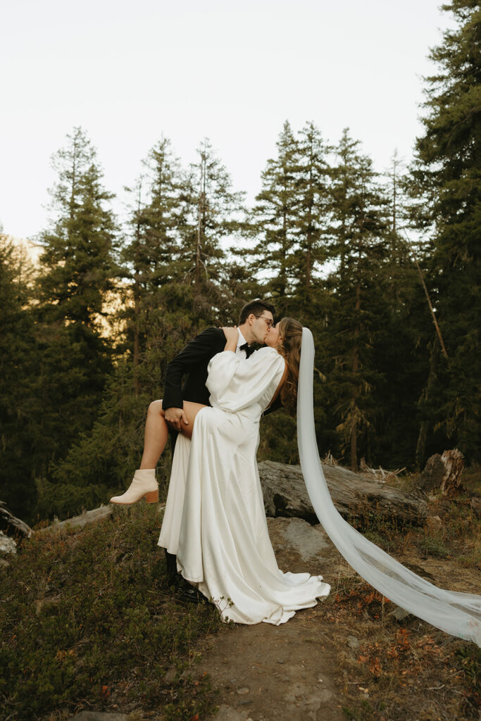 A couple in their wedding wardrobe share a passionate kiss following their Icicle Road elopement