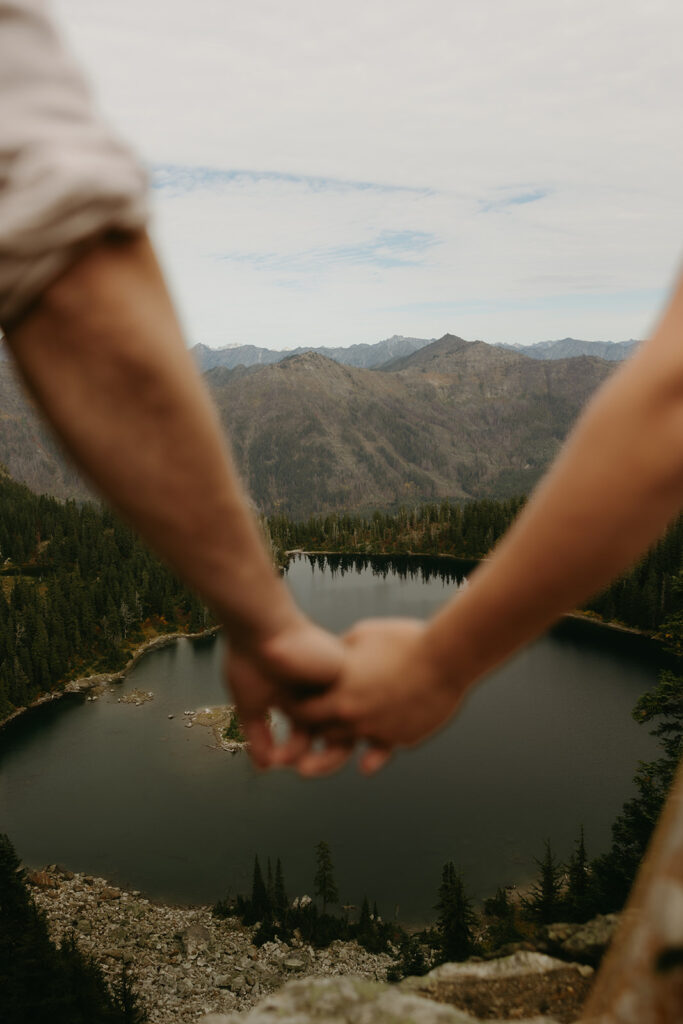 A WA elopement location, Minotaur Lake, is shown from an elevated angle in a photo that includes newlyweds holding hands out of focus in the foreground