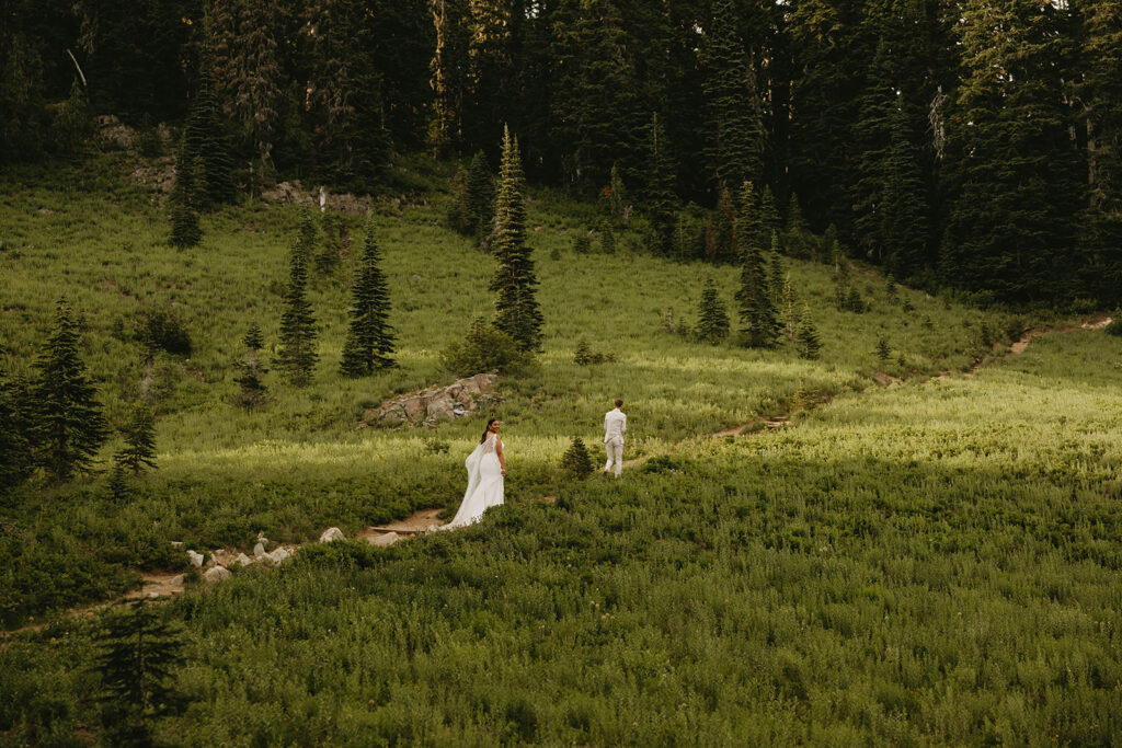 A couple wearing their wedding clothes hikes a short path at Tipsoo Lake following their Washington elopement