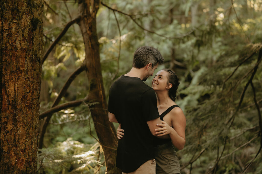Seattle engagement photography captures a Washington couple embracing beneath the pines during their adventure engagement photos