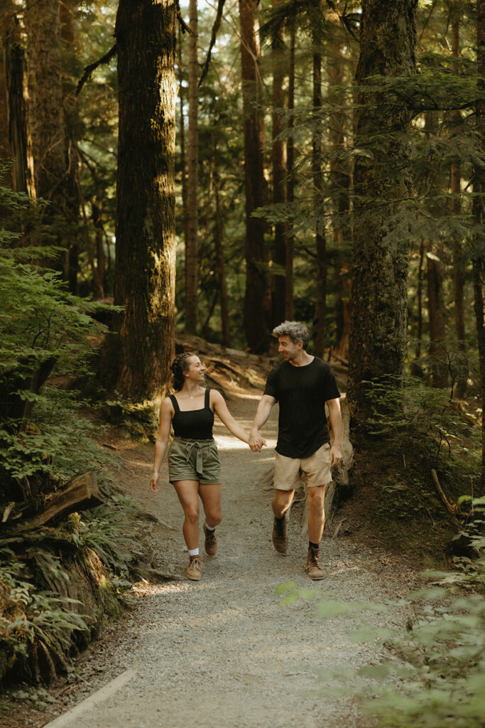 A couple is photographed holding hands as they hike a trail at Franklin Falls WA in Seattle engagement photography 