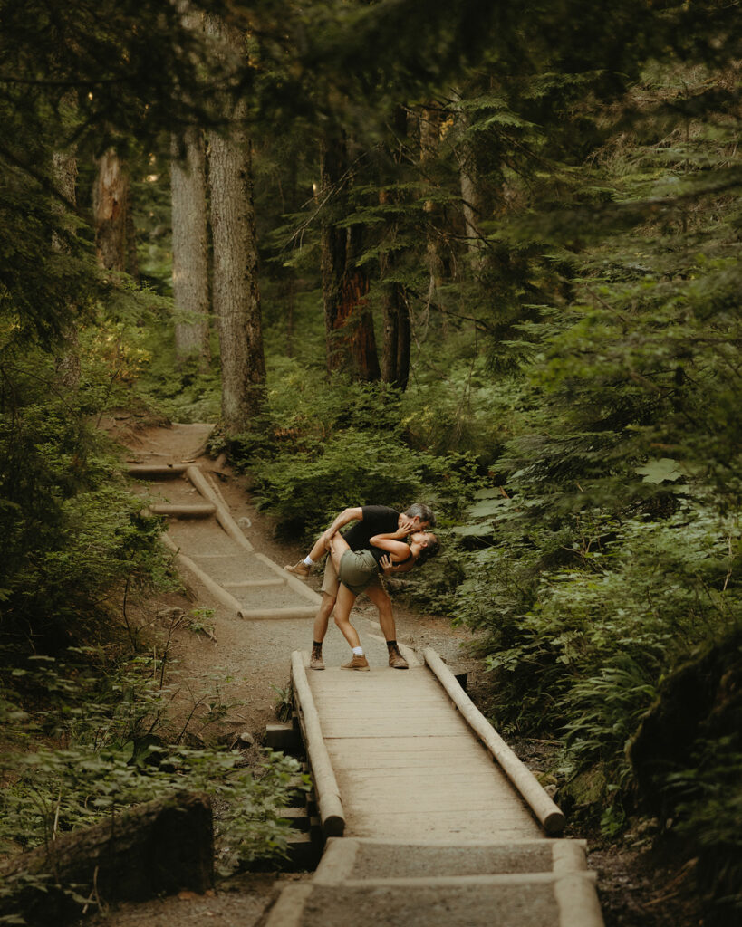 A Washington state man dips his fiancee for a kiss on a hike to Franklin Falls during their adventure engagement photos 