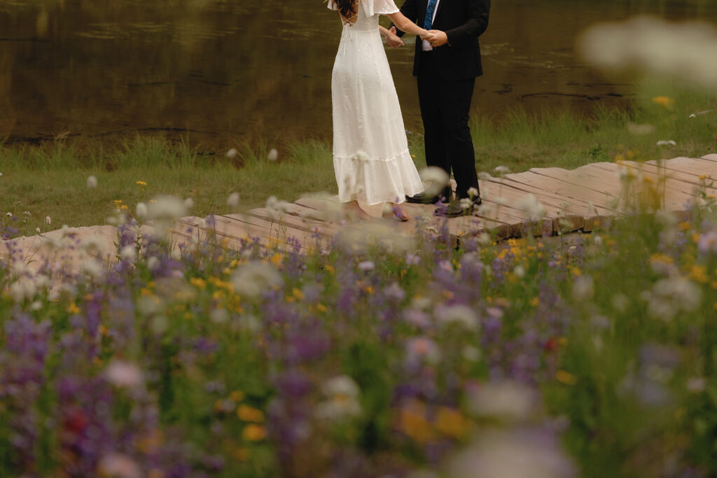 A couple is photographed at a distance surrounded by the wildflowers at their Tipsoo Lake ceremony, one of many beautiful mt rainier wedding locations