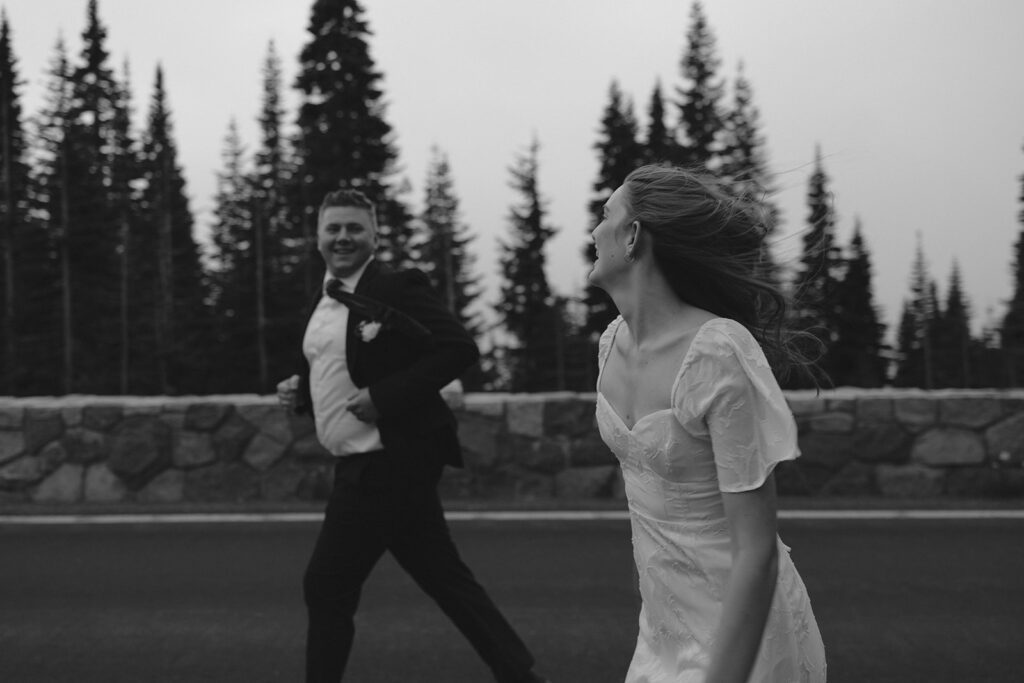 Newlyweds run side by side laughing after their Mount Rainier wedding near Tipsoo Lake