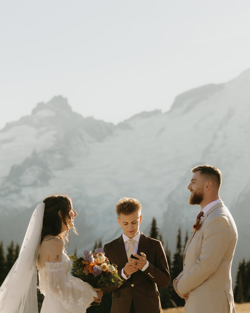 A bride & groom exchange vows at their Mount Rainier wedding ceremony with mountains in the background