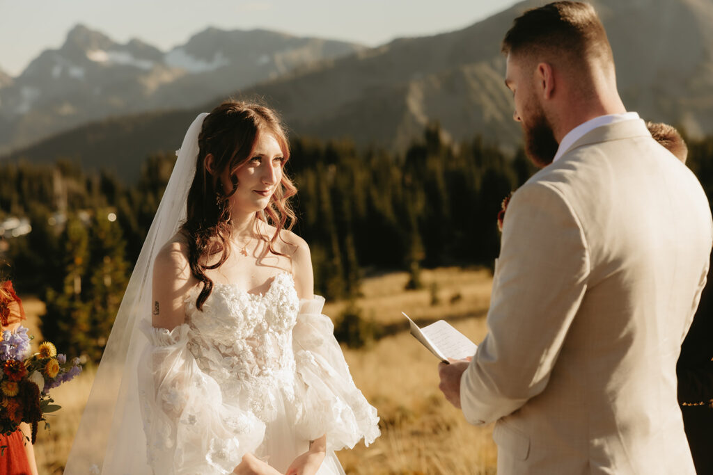 A groom reads handwritten vows to his bride at their mount rainier national park elopement