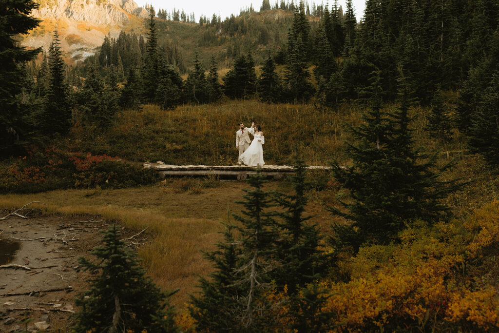 Newlyweds are photographed at a distance while exploring for bridal portraits following their mount rainier national park elopement