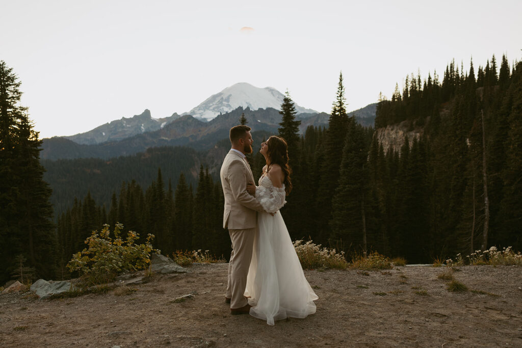 Newlyweds embrace in their wedding attire overlooking the alpines and mountains at their Mount Rainier wedding