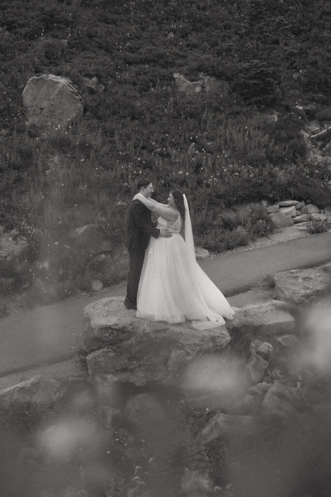 A black and white image of newlyweds sharing an embrace at Paradise following their Mt Rainier wedding ceremony 