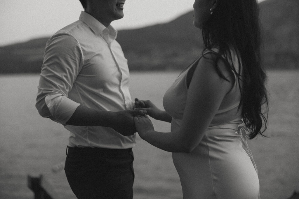A black and white photo depicts an engaged couple holding hands during a photoshoot with Washington engagement photographer
