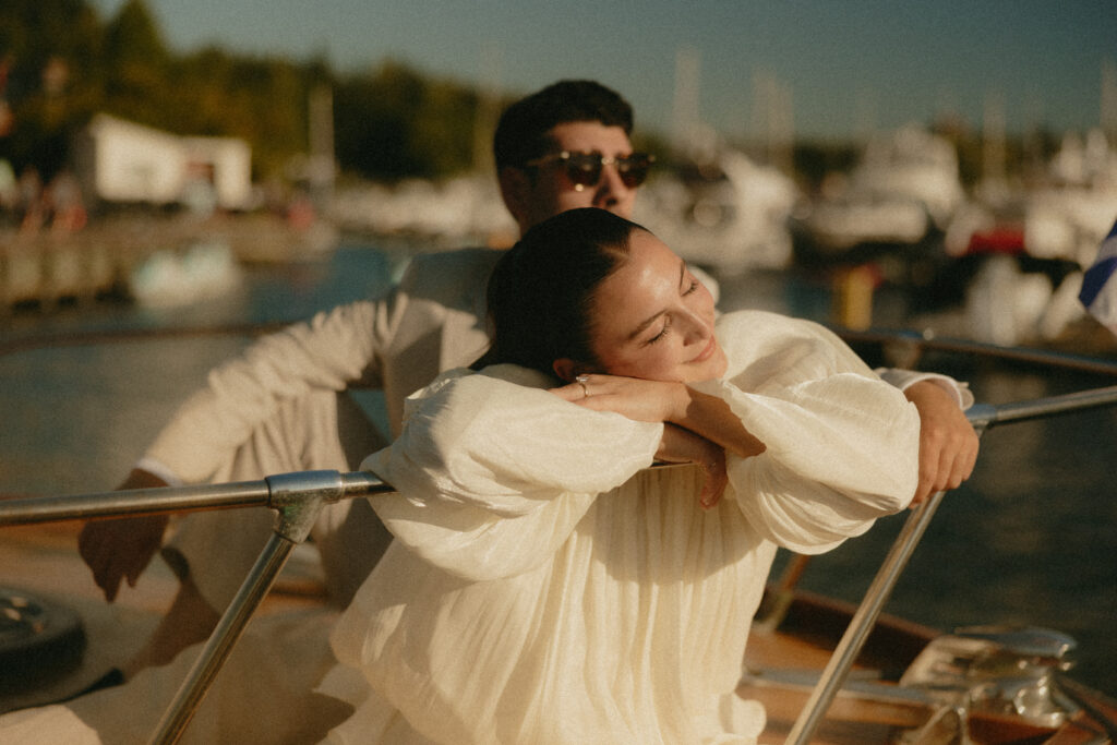 A woman leaning over the railing of a boat in a white dress