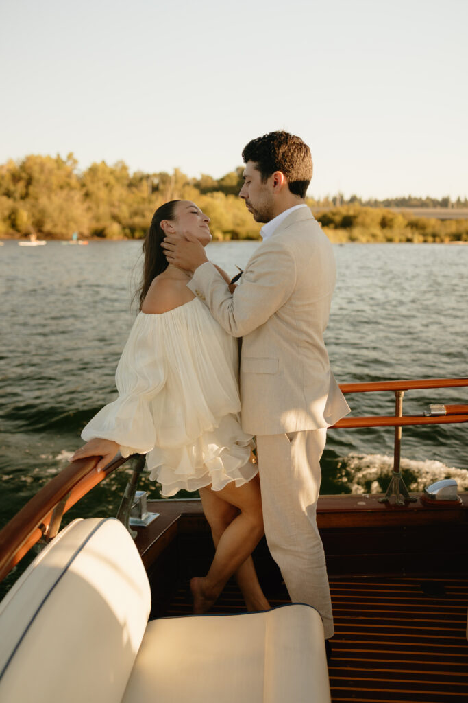 A couple wearing white looking at each other in the back of a boat