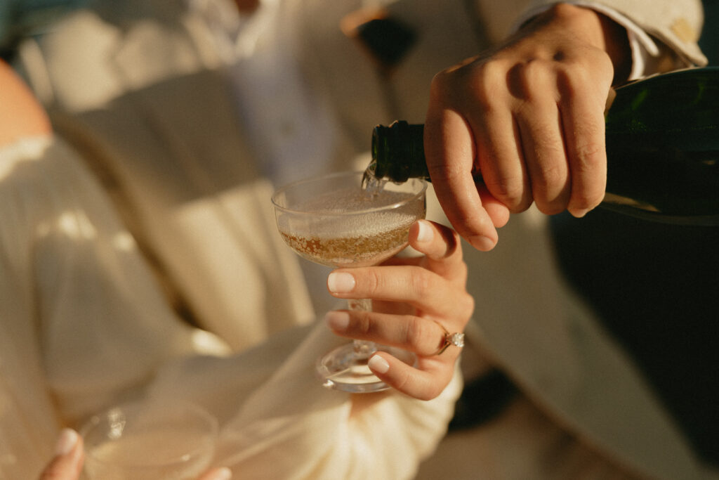 A couple pouring each other champagne during their engagement session in Seattle
