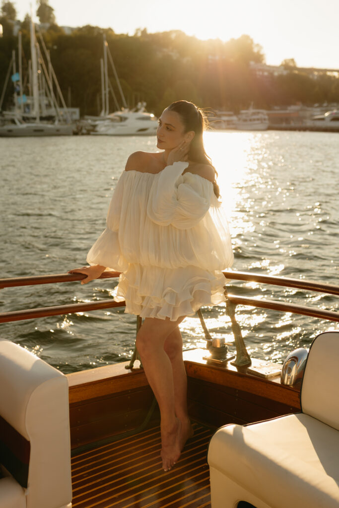 A woman wearing white leaning over the back of a boat on Lake Union