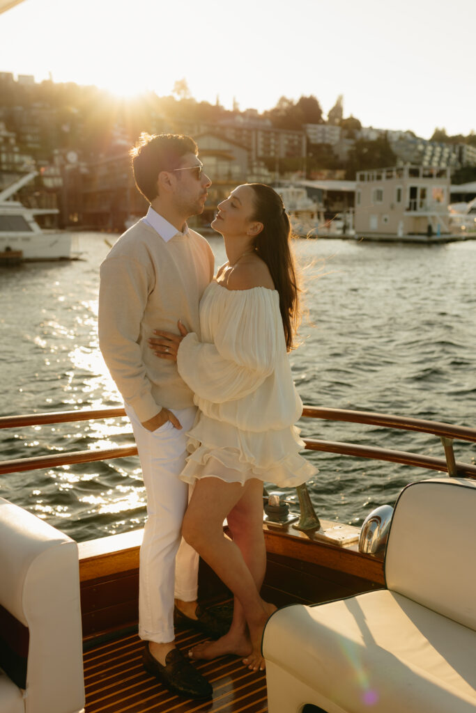 A couple wearing white standing together in the back of a boat on Lake Union