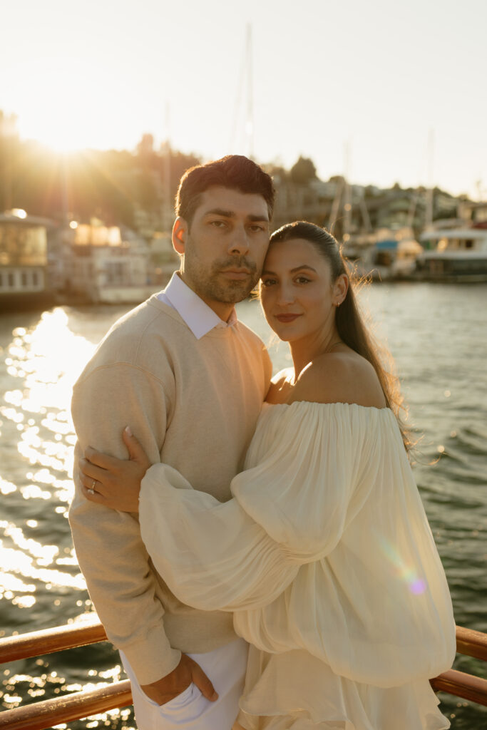 A couple wearing white standing together in the back of a boat on Lake Union