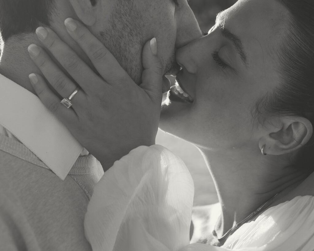A black and white photo of a couple kissing during their engagement session