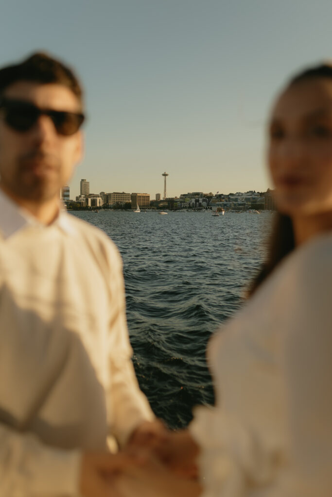 An out of focus couple looking at the camera with the Space Needle behind them